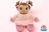 Madina Islamic Teaching Plush toy resembling a baby with brown hair and pink bows on a pink background. Muslim doll Madina reciting Surah Al-Fatiha