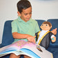 Child reading a book with a muslim doll on a blue couch. Close-up of Khaled doll’s smiling face. Muslim plush toy for toddlers.